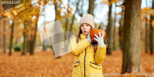 Image of happy girl with pumpkin at autumn park