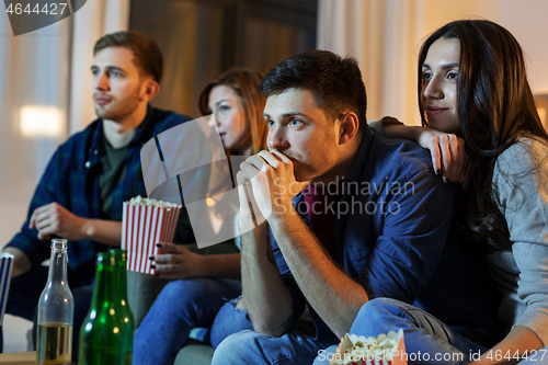 Image of friends with beer and popcorn watching tv at home