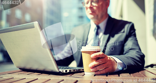 Image of senior businessman with laptop and coffee outdoors