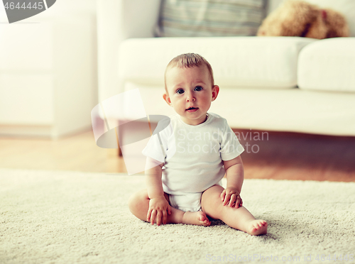 Image of happy baby boy or girl sitting on floor at home