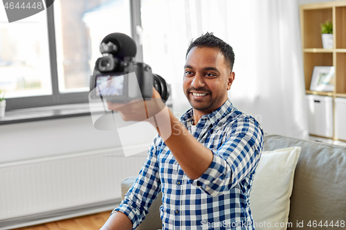 Image of male video blogger with camera blogging at home