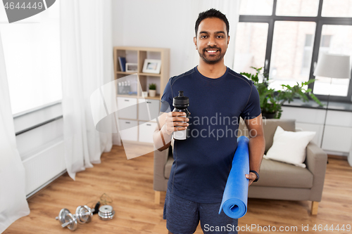 Image of indian man with exercise mat and bottle at home