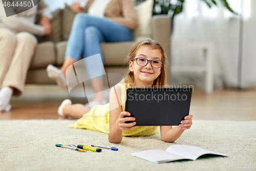 Image of student girl with tablet pc lying on floor at home