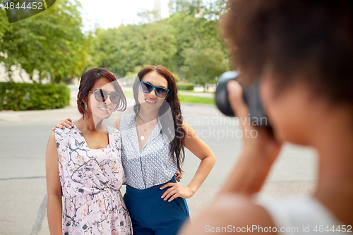 Image of woman photographing her friends in summer park