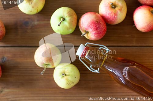 Image of bottle of apple juice or vinegar on wooden table