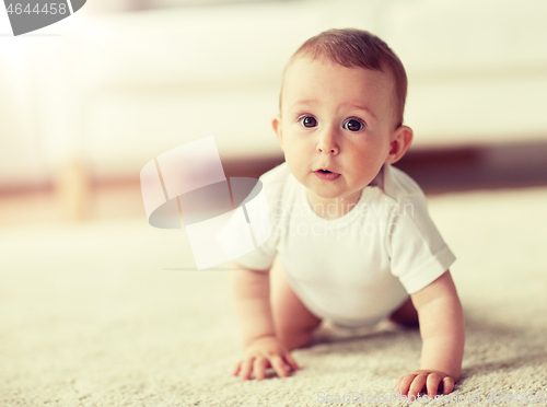 Image of little baby in diaper crawling on floor at home