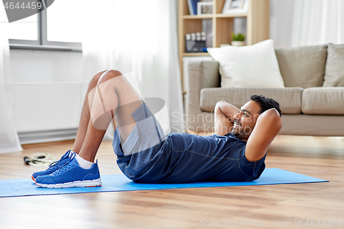 Image of indian man making abdominal exercises at home