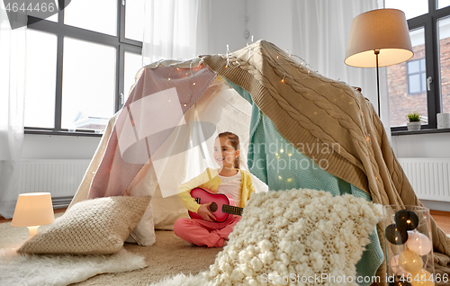 Image of little girl playing guitar in kids tent at home