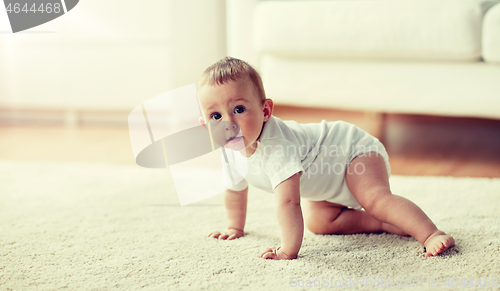 Image of little baby in diaper crawling on floor at home