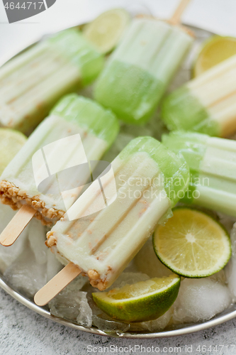 Image of Summer refreshing homemade lime popsicles with chipped ice over stone background