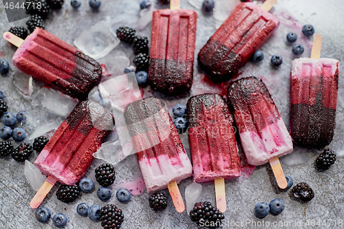 Image of Homemade blackberry and cream ice-creams or popsicles with frozen berries on black slate tray