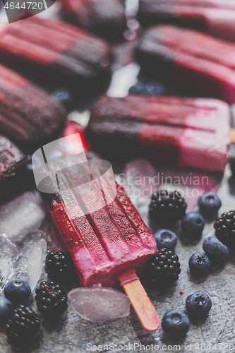 Image of Homemade blackberry and cream ice-creams or popsicles with frozen berries on black slate tray