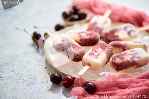 Image of Fresh cream and cherry homemade popsicles placed on white ceramic plate with fruits and textile