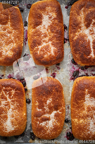 Image of Delicious hot homemade buns stuffed with blueberry on a baking tray