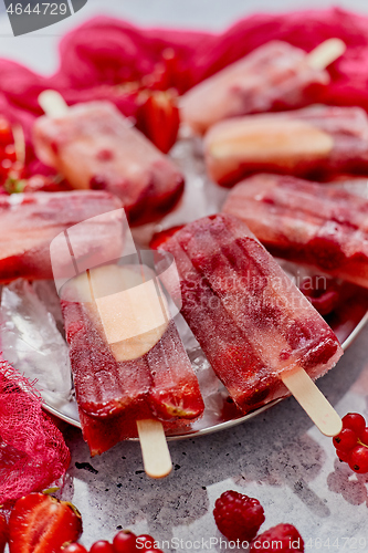 Image of Strawberry raspberry apple and red currant ice cream popsicles in metal tray with ice cubes