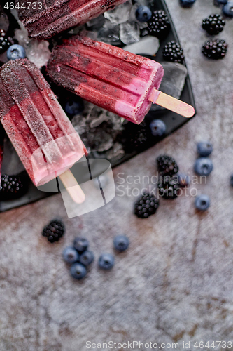 Image of Forrest fruit ice cream on stick. Homemade healthy vegan snack. Placed on plate with ice