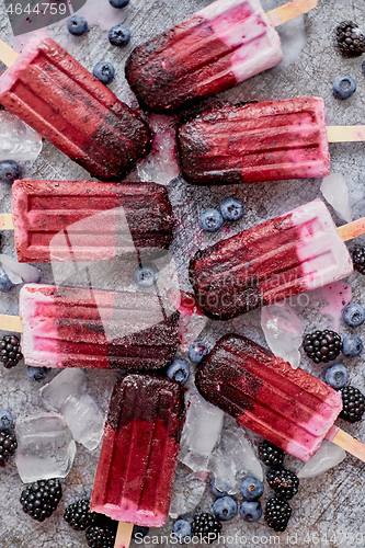 Image of Homemade blackberry and cream ice-creams or popsicles with frozen berries on black slate tray