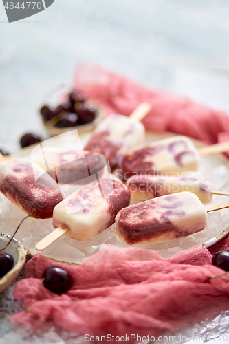 Image of Homemade vegan cherry popsicles with coconut milk. Placed on ceramic plate