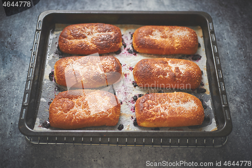 Image of Delicious hot homemade buns stuffed with blueberry on a baking tray