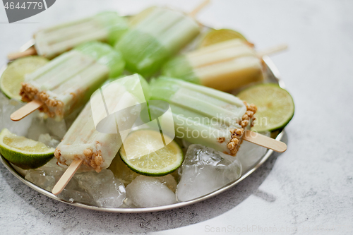 Image of Summer refreshing homemade lime popsicles with chipped ice over stone background
