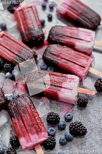 Image of Homemade blackberry and cream ice-creams or popsicles with frozen berries on black slate tray