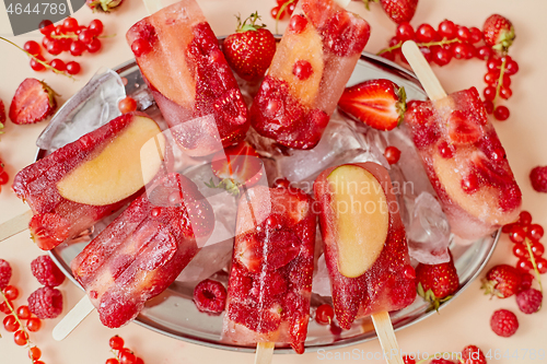 Image of Strawberry raspberry apple and red currant ice cream popsicles in metal tray with ice cubes