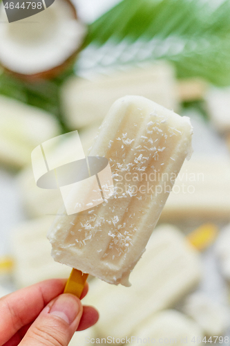 Image of Closeup on hand holding homemade pineapple coconut popsicle. Summer food concept.