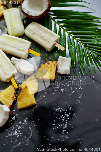 Image of Homemade pineapple coconut popsicles on stone background. Summer food concept with copy space