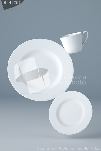 Image of Mockup of two white plates and a cup levitating on blue background