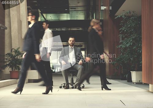 Image of business man sitting in office chair, people group  passing by