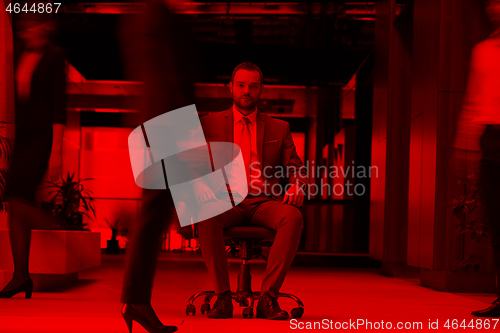 Image of business man sitting in office chair, people group  passing by