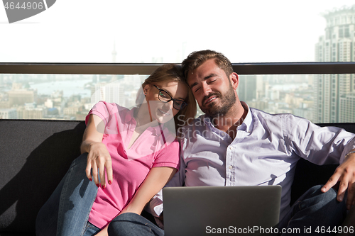 Image of couple relaxing at  home using laptop computers