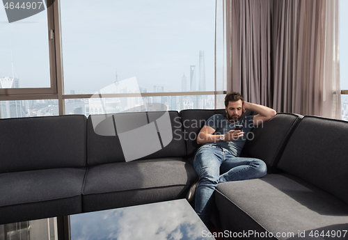 Image of young casual man using a mobile phone at home