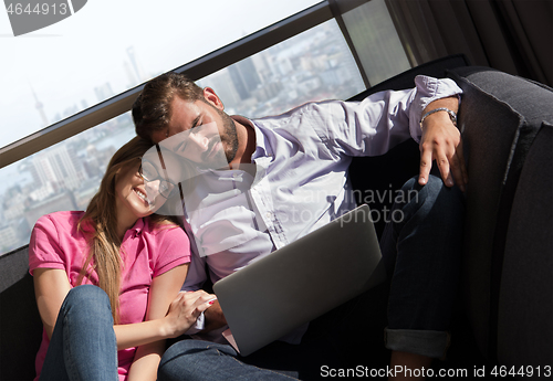 Image of couple relaxing at  home using laptop computers