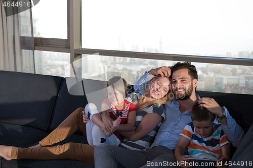 Image of happy young couple spending time with kids at home