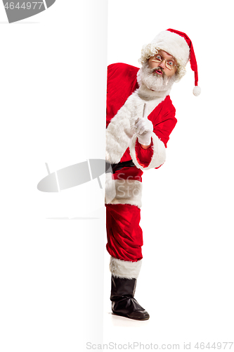 Image of Happy Santa Claus pointing on blank advertisement banner background with copy space. Smiling Santa Claus pointing in white blank sign