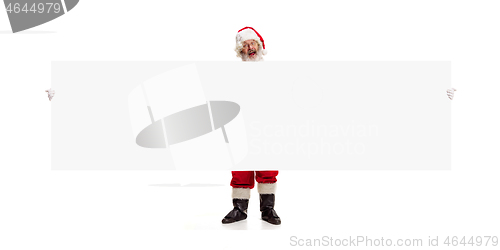 Image of Happy Santa Claus pointing on blank advertisement banner background with copy space. Smiling Santa Claus pointing in white blank sign