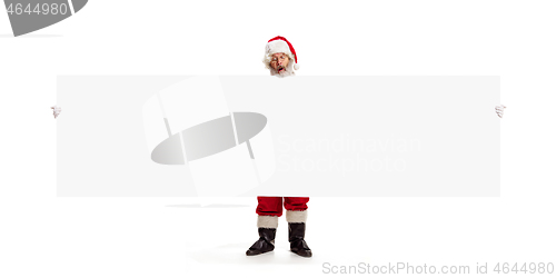 Image of Happy Santa Claus pointing on blank advertisement banner background with copy space. Smiling Santa Claus pointing in white blank sign