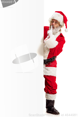 Image of Happy Santa Claus pointing on blank advertisement banner background with copy space. Smiling Santa Claus pointing in white blank sign