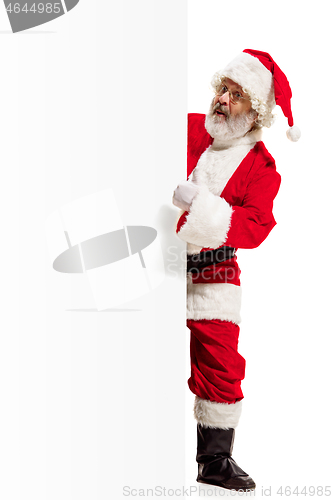 Image of Happy Santa Claus pointing on blank advertisement banner background with copy space. Smiling Santa Claus pointing in white blank sign