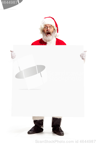 Image of Happy Santa Claus pointing on blank advertisement banner background with copy space. Smiling Santa Claus pointing in white blank sign