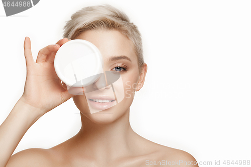 Image of Cute girl preparing to start her day. She is applying moisturizer cream on face.