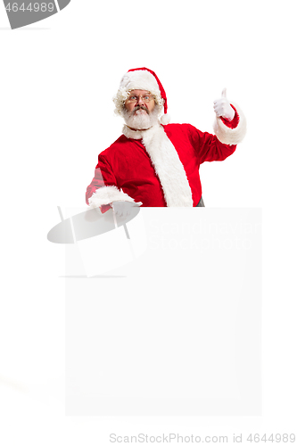 Image of Happy Santa Claus pointing on blank advertisement banner background with copy space. Smiling Santa Claus pointing in white blank sign