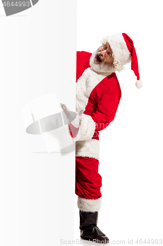 Image of Happy Santa Claus pointing on blank advertisement banner background with copy space. Smiling Santa Claus pointing in white blank sign