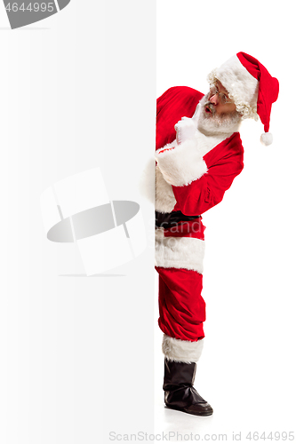 Image of Happy Santa Claus pointing on blank advertisement banner background with copy space. Smiling Santa Claus pointing in white blank sign