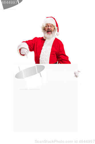 Image of Happy Santa Claus pointing on blank advertisement banner background with copy space. Smiling Santa Claus pointing in white blank sign