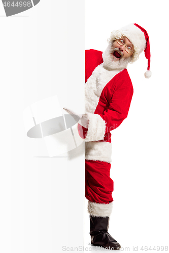 Image of Happy Santa Claus pointing on blank advertisement banner background with copy space. Smiling Santa Claus pointing in white blank sign