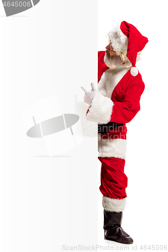 Image of Happy Santa Claus pointing on blank advertisement banner background with copy space. Smiling Santa Claus pointing in white blank sign