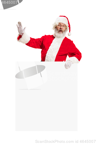 Image of Happy Santa Claus pointing on blank advertisement banner background with copy space. Smiling Santa Claus pointing in white blank sign