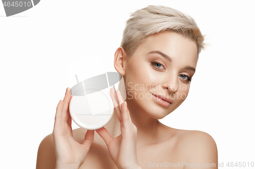 Image of Cute girl preparing to start her day. She is applying moisturizer cream on face.